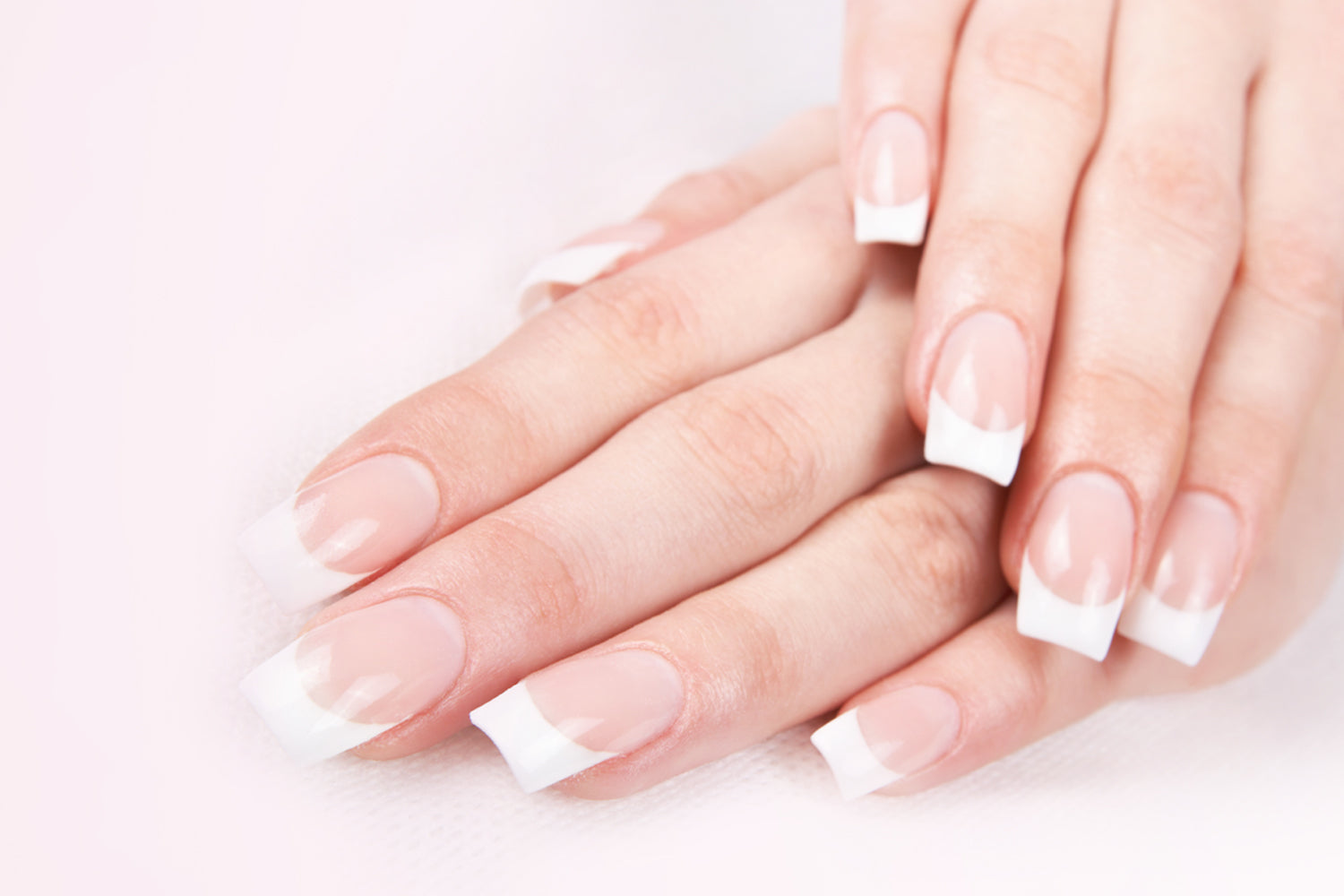 Well-manicured fingers with classic French tip nail design.