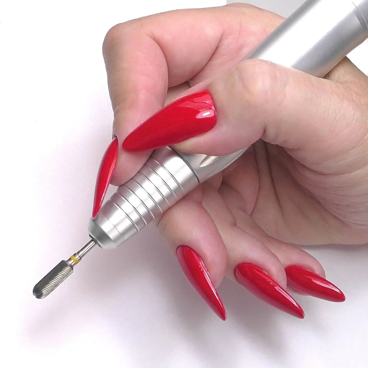 Hand with long red stiletto nails holding a silver nail drill.
