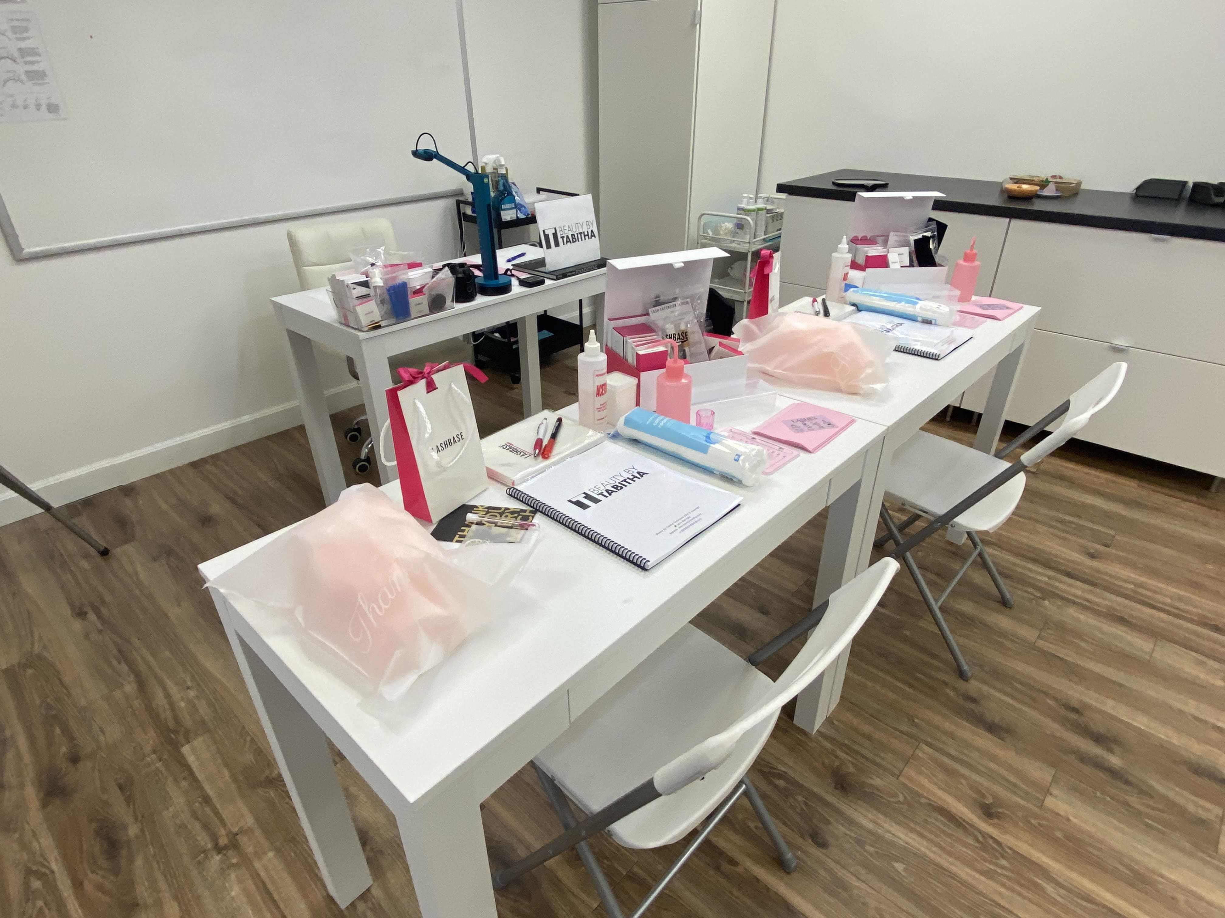 two white desks with eyelash extension supplies