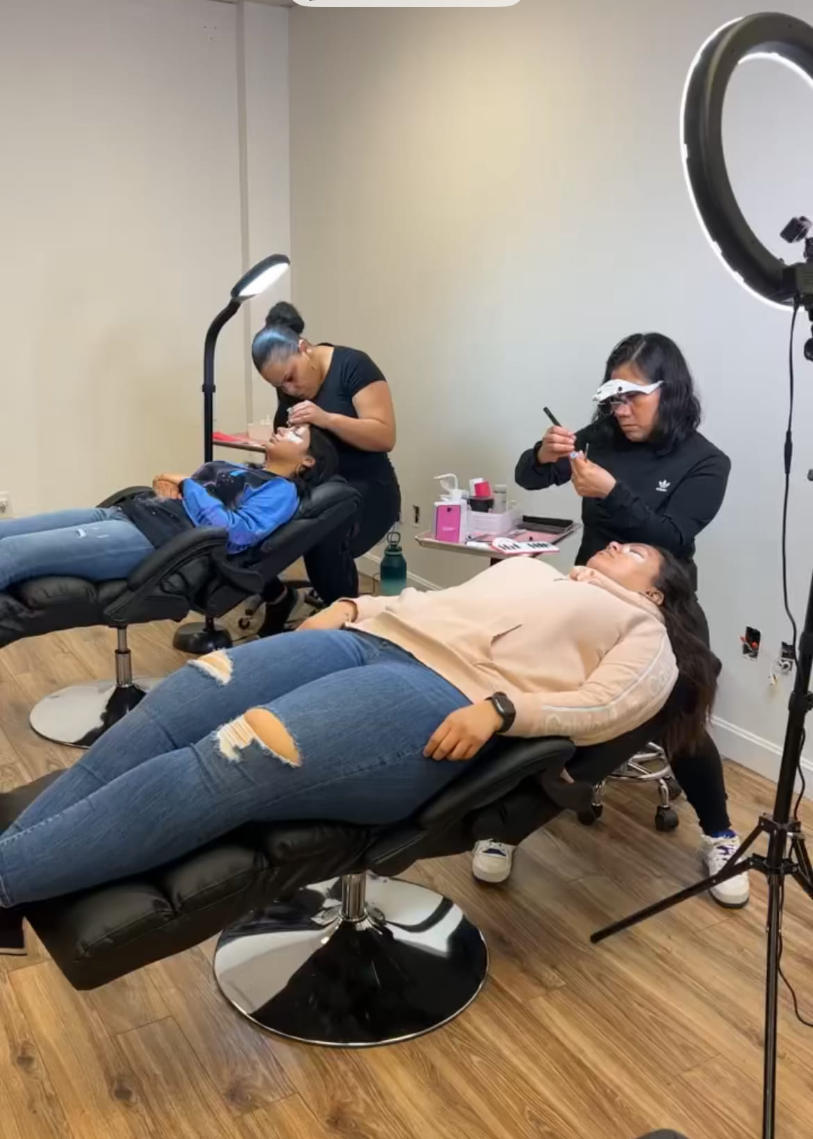 two women practicing eyelash extensions on clients
