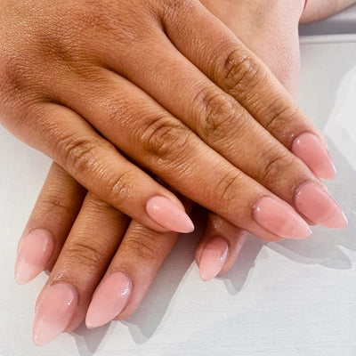 Close-up of two hands with pink nail polish on a light background