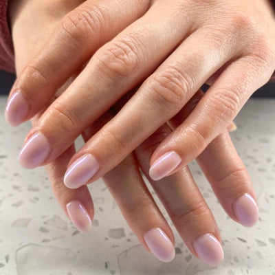 Close-up of hands with pink nail polish on a light background