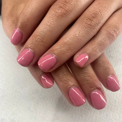 Close-up of hands with pink nail polish on a white background