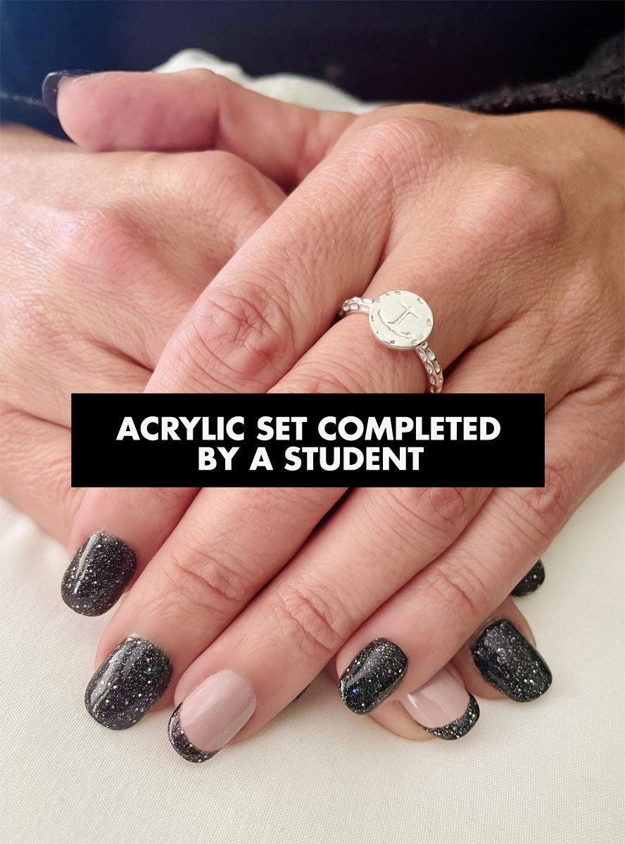 Sparkly black acrylic nails with one nude accent nail and a diamond engagement ring.