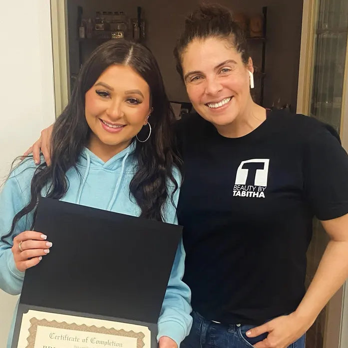 Two people posing together while holding a certificate or diploma.